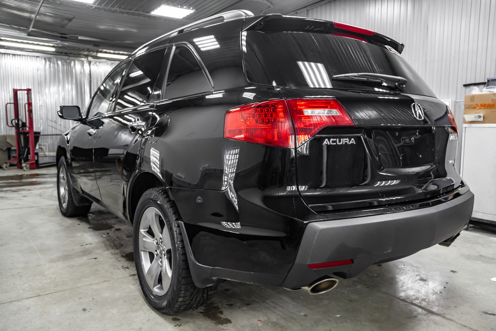 A black Acura inside a brightly lit auto garage